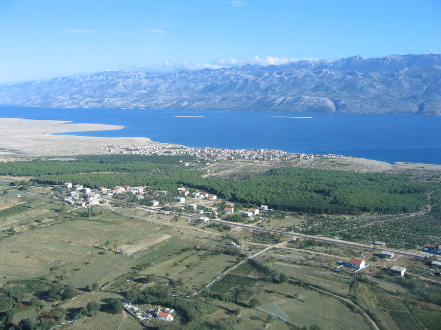 Ražanac iz zraka, s pogledom prema Velebitskom kanalu i Velebitu. Položaj mjesta dobro pokazuje prostor na kojem se u 17. stoljeću, na mletačko-osmanskoj granici, odvijala i priča o otvaranju grobova i crkvenoj istrazi zbog vjerovanja u vukodlake. Foto: Općina Ražanac.