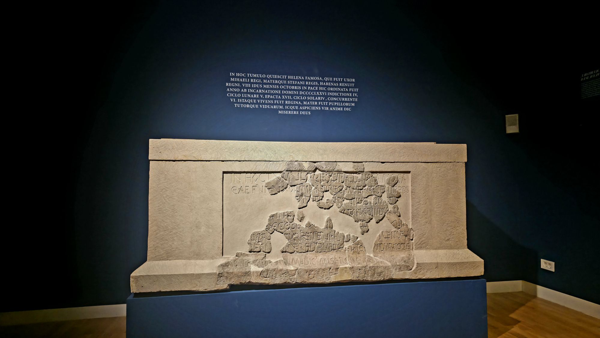 Rekonstruirani sarkofag hrvatske kraljice Jelene s ulomcima epitafa pronađenima 1898. na Gospinu otoku u Solinu. Natpis iz 976. godine jedan je od ključnih pisanih izvora za hrvatsku vladarsku dinastiju i kraljevski mauzolej u Solinu. Izložba „U početku bijaše kraljevstvo“.